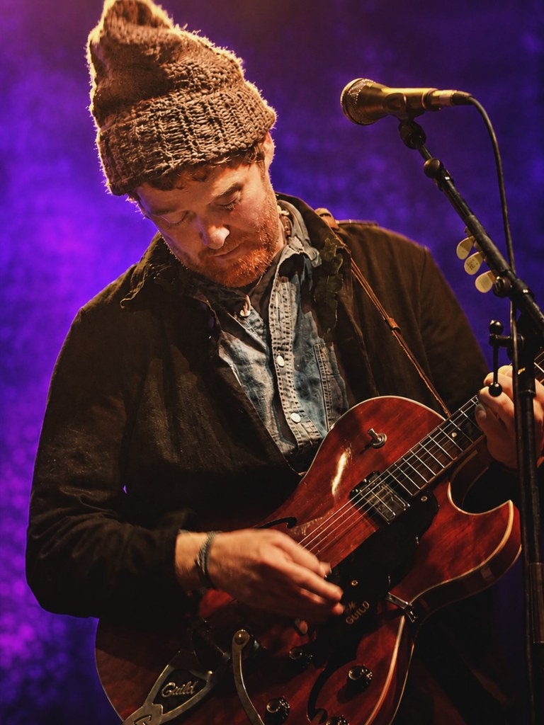 Glen Hansard performing on stage in Cork, caught mid-song in warm stage light.